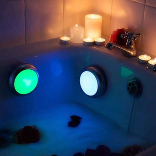 An image of two bath spa lights in the bath, one is green and one is giving off white light.