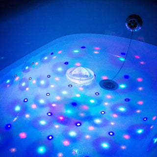 A photo of a bath light floating in the bath with vivid colours.