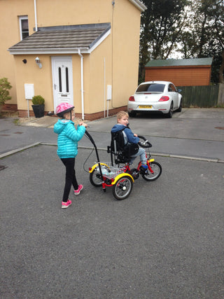 Sister pushing brother on Adapted Trike