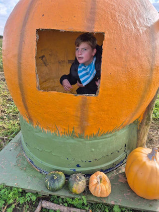 Child with additional needs sitting inside a pumpkin house during a sensory-friendly Halloween celebration