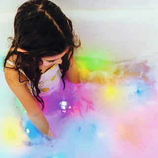 Child enjoying a sensory bath with multicolored Glo Pals light-up cubes, creating a glowing and engaging water play experience.
