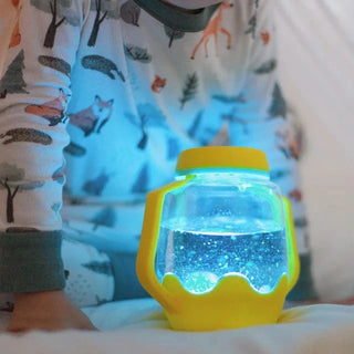 Close-up of a child holding a Glo Pals Sensory Jar with glowing blue lights inside, offering a soothing sensory experience for kids with additional needs.