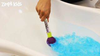 Magic paintbrush in a bath with blue fizzing water from Zimpli Baff Bombz, creating a colorful sensory experience